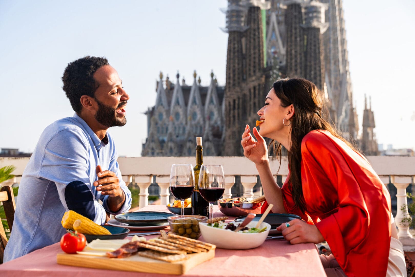 Multiracial beautiful happy couple of lovers dating on rooftop balcony at Sagrada Familia, Barcelona - Multiethnic people having romantic aperitif dinner on a terrace with city view , concepts about tourism and people lifestyle