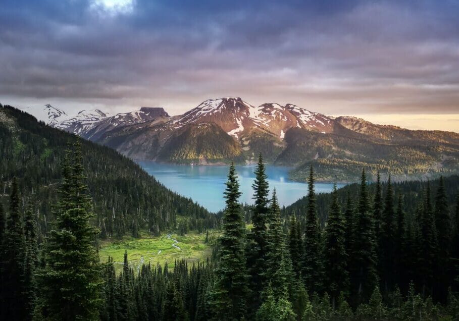 Mountain lake with forest and cloudy sky.